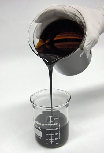 Furnace oil poured from a steel jug into a glass beaker