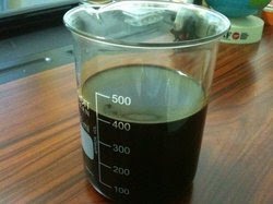 A 500 ml beaker of light diesel oil on a wooden bench